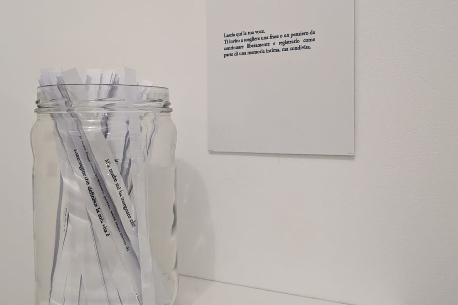 Un barattolo pieno di strisce di carta con frasi da continuare, accanto al cartello «Lascia qui la tua voce»