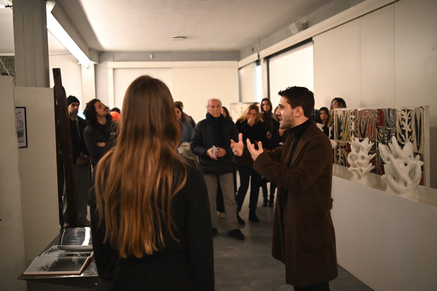 Lorenzo racconta Radici a un gruppo di persone in piedi nella galleria